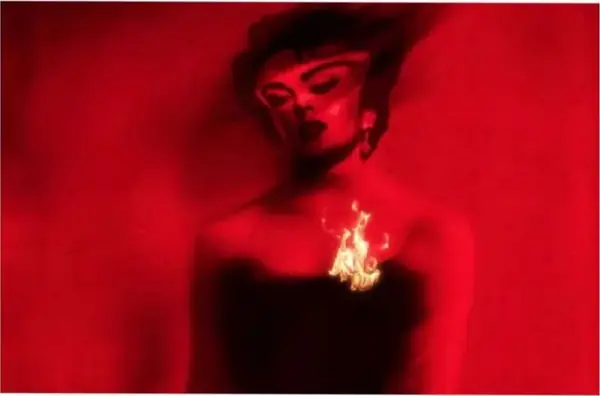 Retrato fotográfico em tons de vermelho de uma mulher de cabelo escuro com uma pequena chama sobre o peito