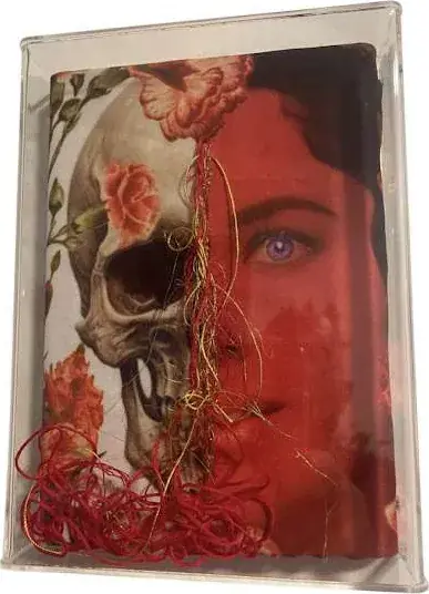 Moldura de acrílico com retrato em que metade do rosto se revela como caveira, com bordado vermelho